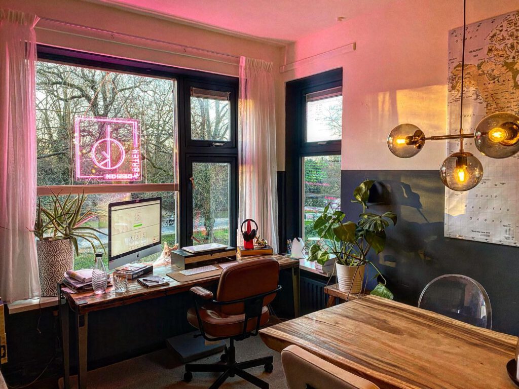 Homeoffice with pink neon sign sign of logo in the window.